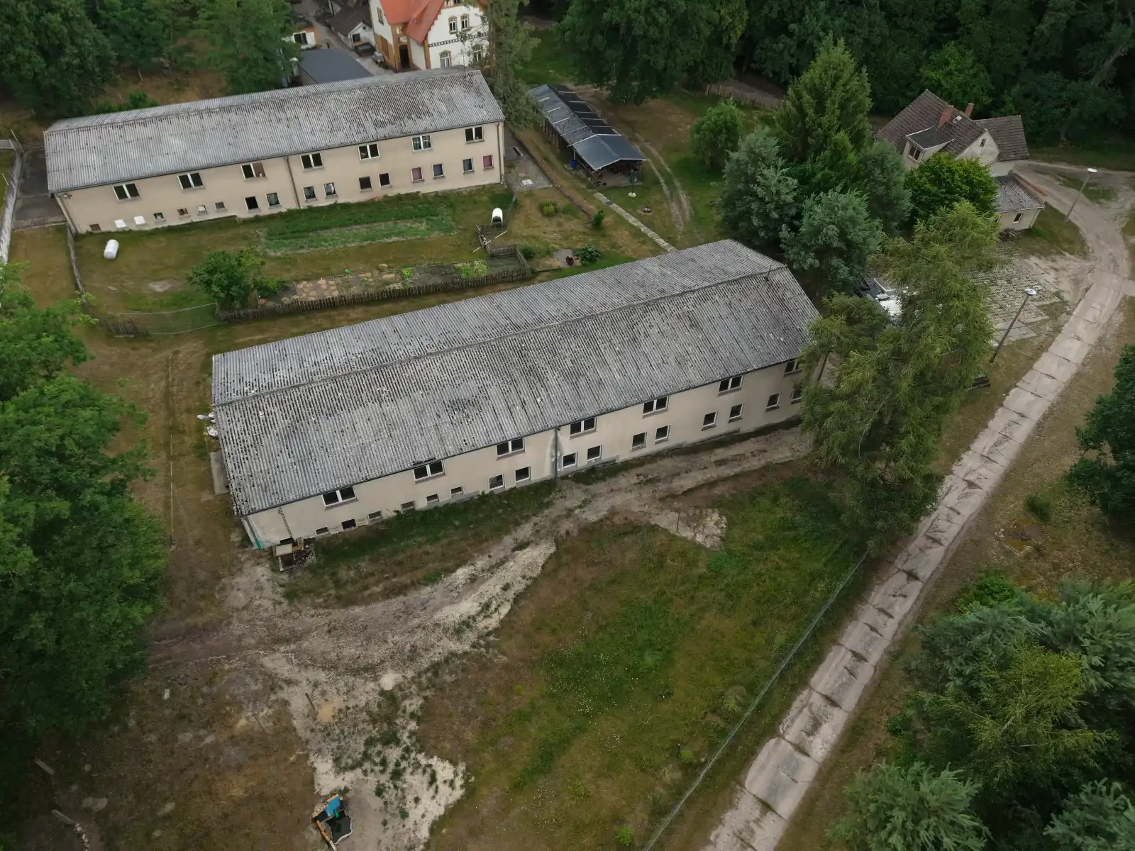 Schräge Drohnenaufnahme der Gebäude um das Forsthaus Parnitz mit Mischwald im Hintergrund