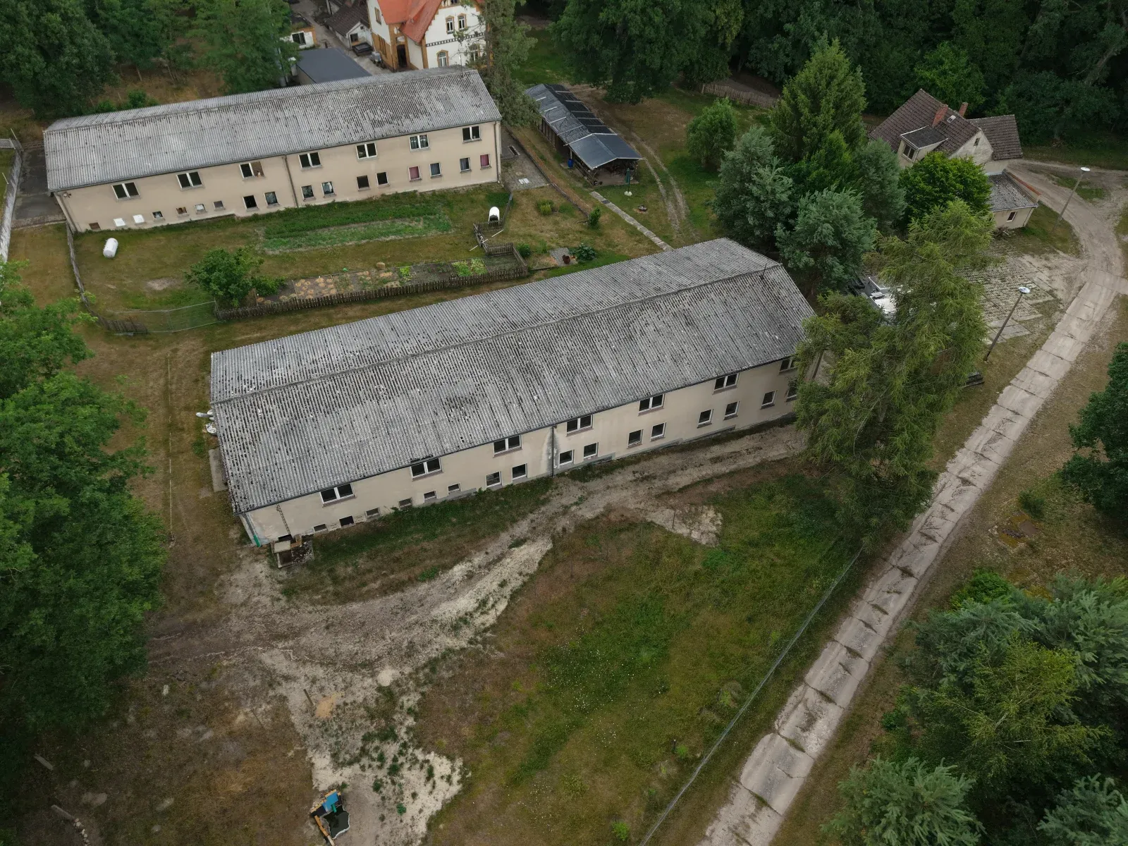 Schräge Drohnenaufnahme der Gebäude um das Forsthaus Parnitz mit Mischwald im Hintergrund