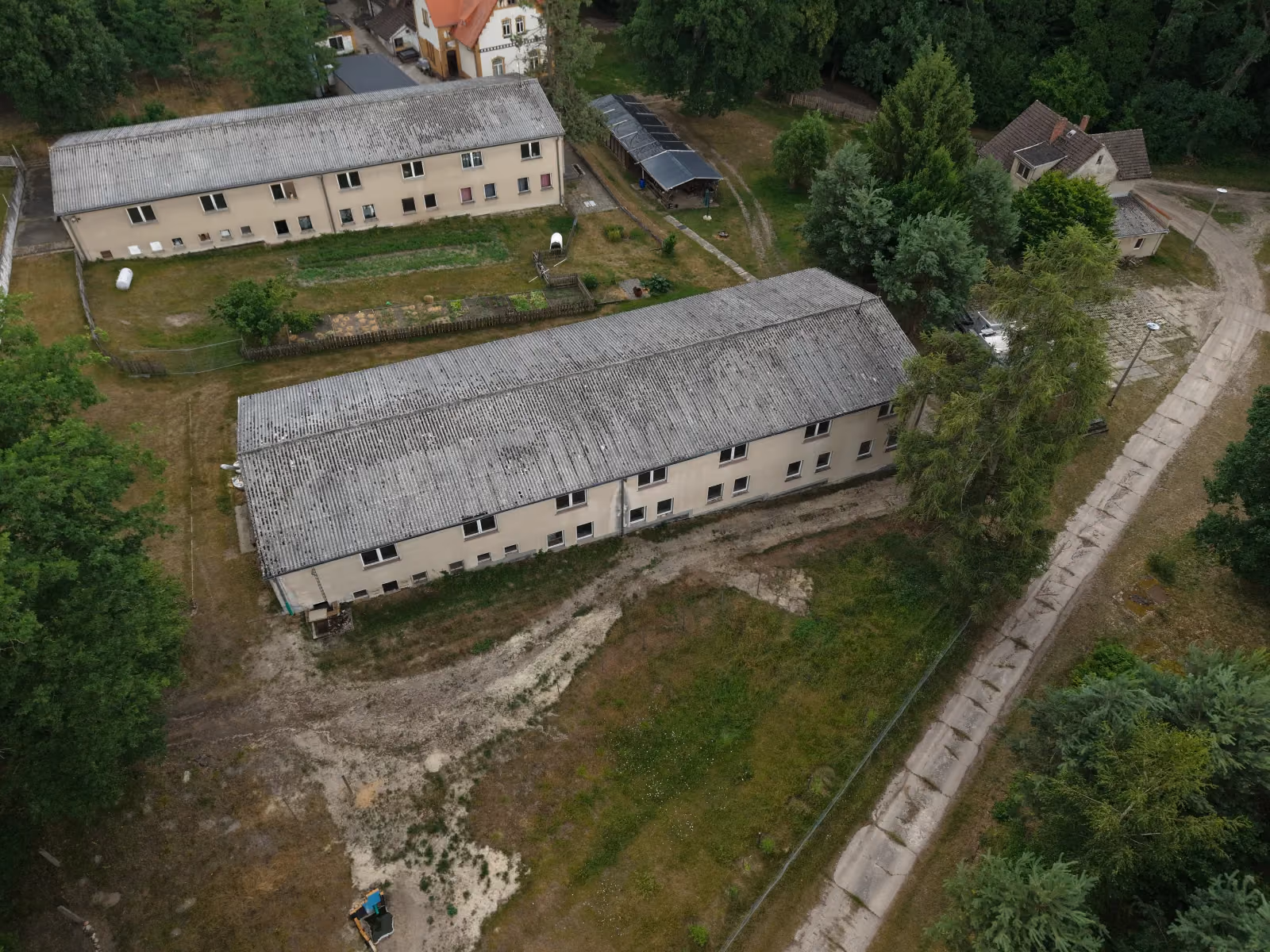 Schräge Drohnenaufnahme der Gebäude um das Forsthaus Parnitz mit Mischwald im Hintergrund