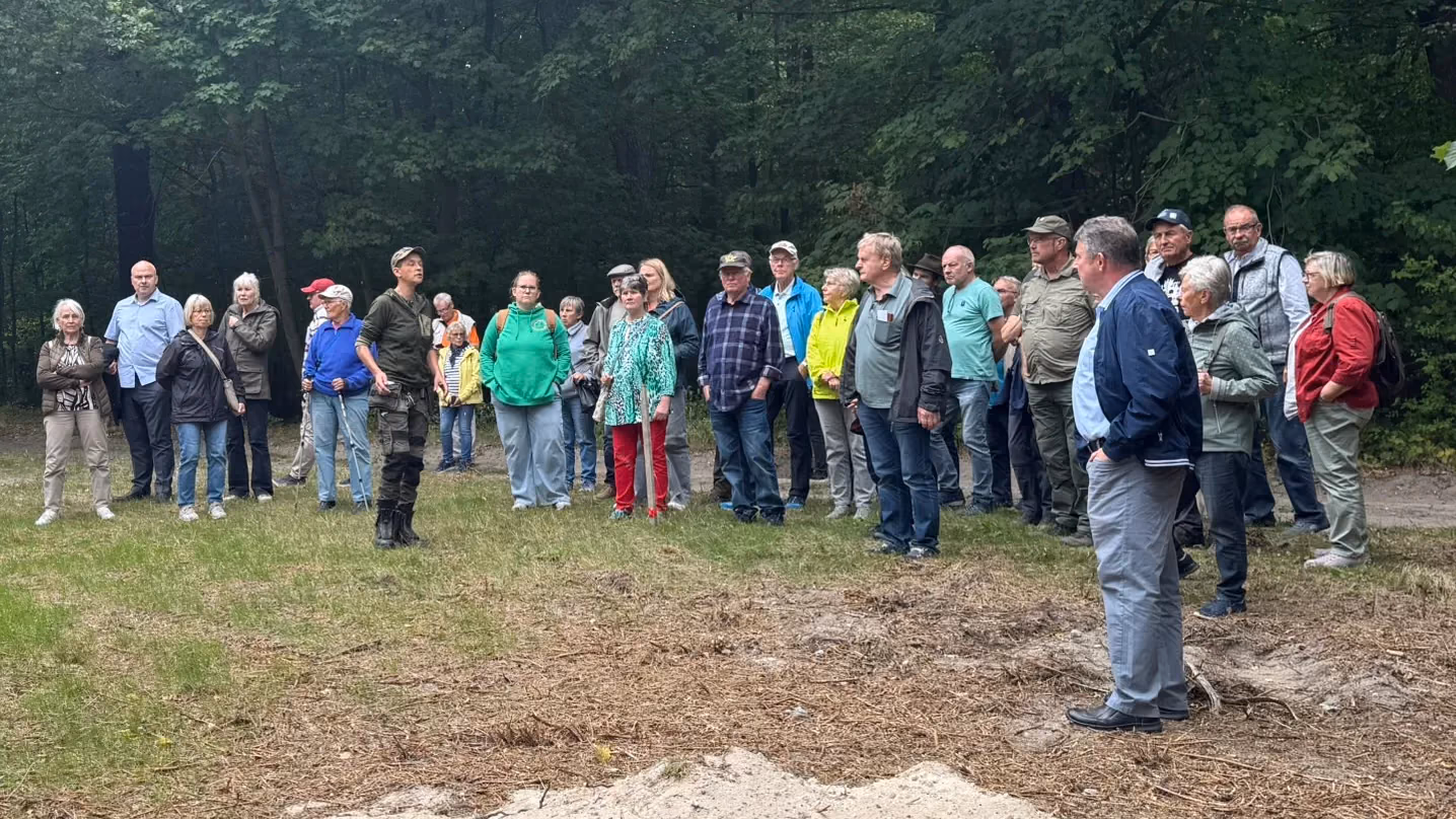 Teilnehmende der Heiderundfahrt 2026 als Halbkreis auf einer Waldlichtung am Forsthaus Parnitz — Susanne Reuter in Forstkleidung erklärt der Gruppe den Standort