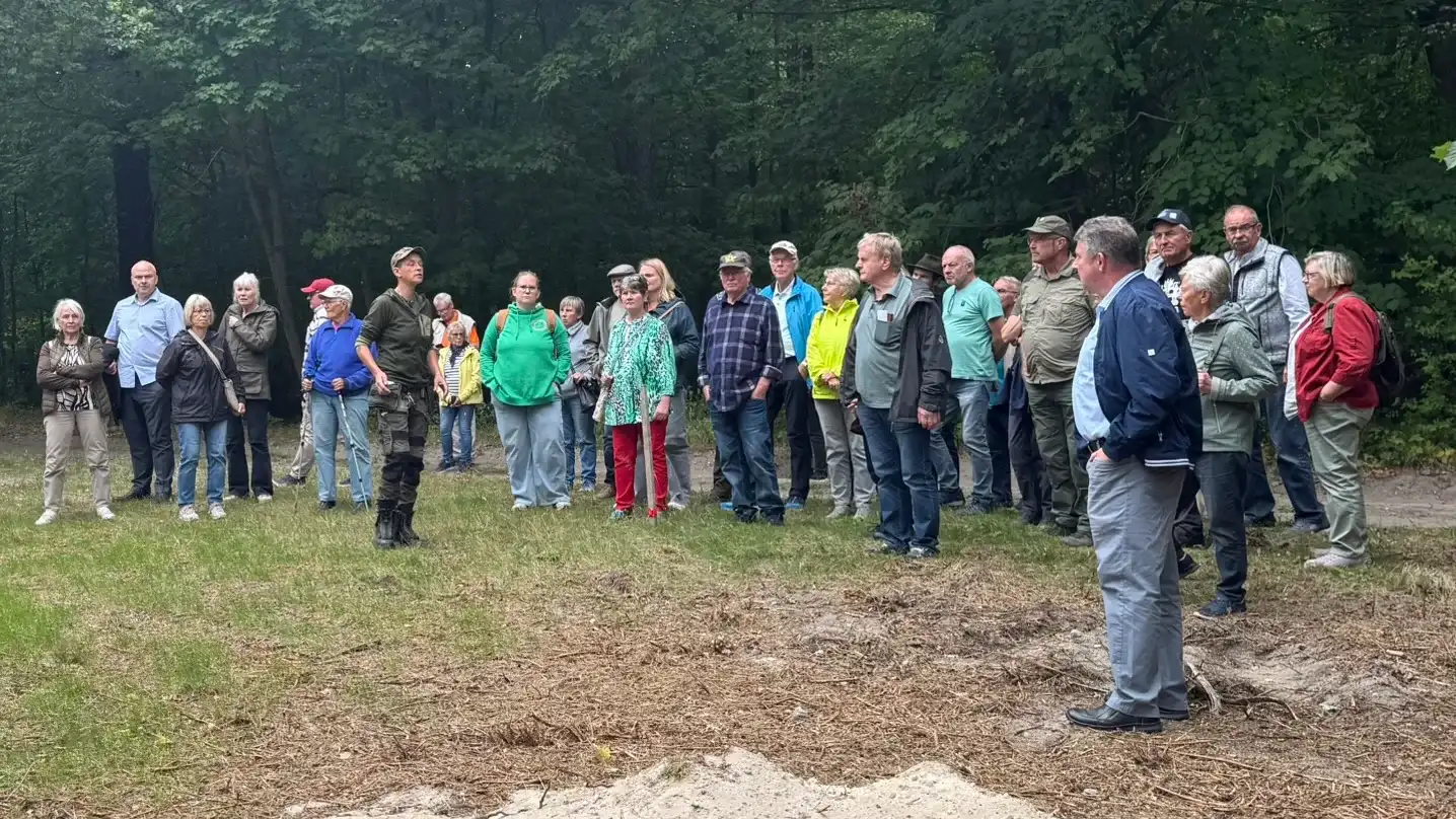 Teilnehmende der Heiderundfahrt 2026 als Halbkreis auf einer Waldlichtung am Forsthaus Parnitz — Susanne Reuter in Forstkleidung erklärt der Gruppe den Standort