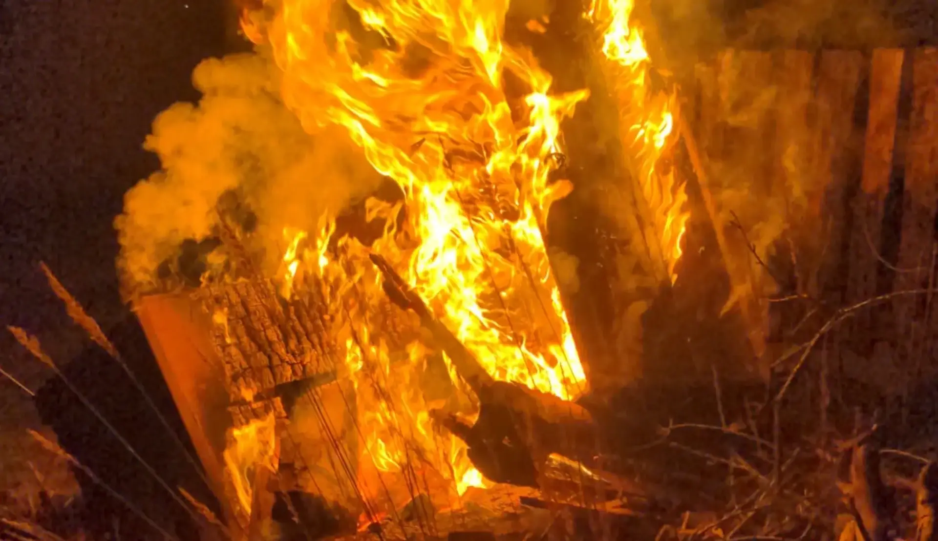 Nächtliche Flamme mit Rauchentwicklung an trockenem Holz und Reisig